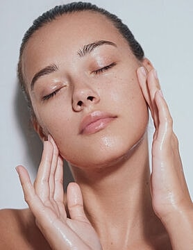Woman with glowy skin touching her face.