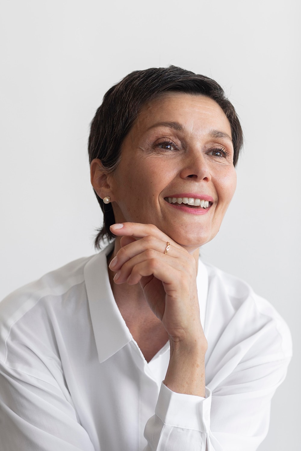 Smiling woman in white shirt, thoughtful pose.