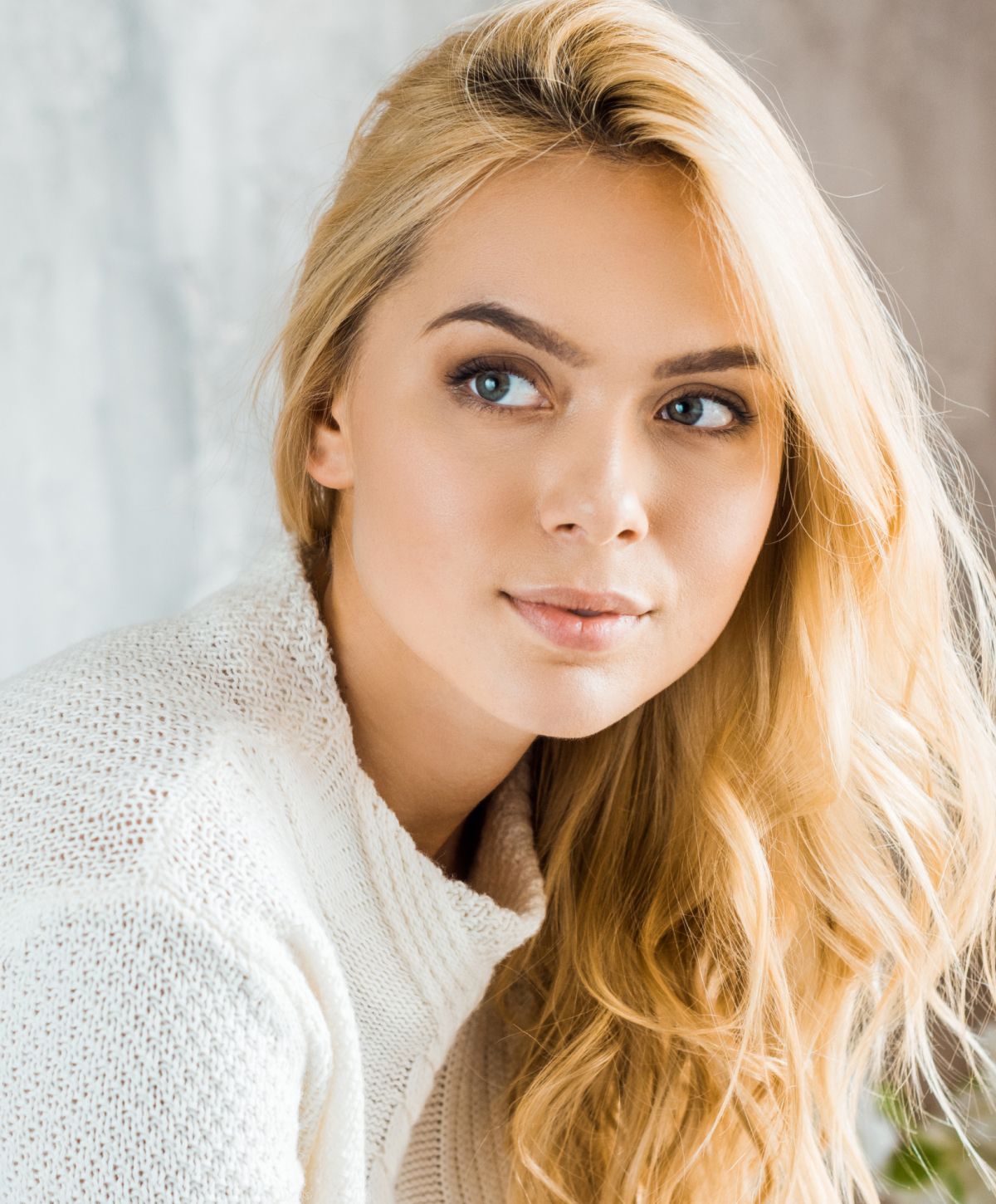 Blonde Newport Beach lower blepharoplasty model in cozy sweater, soft lighting.