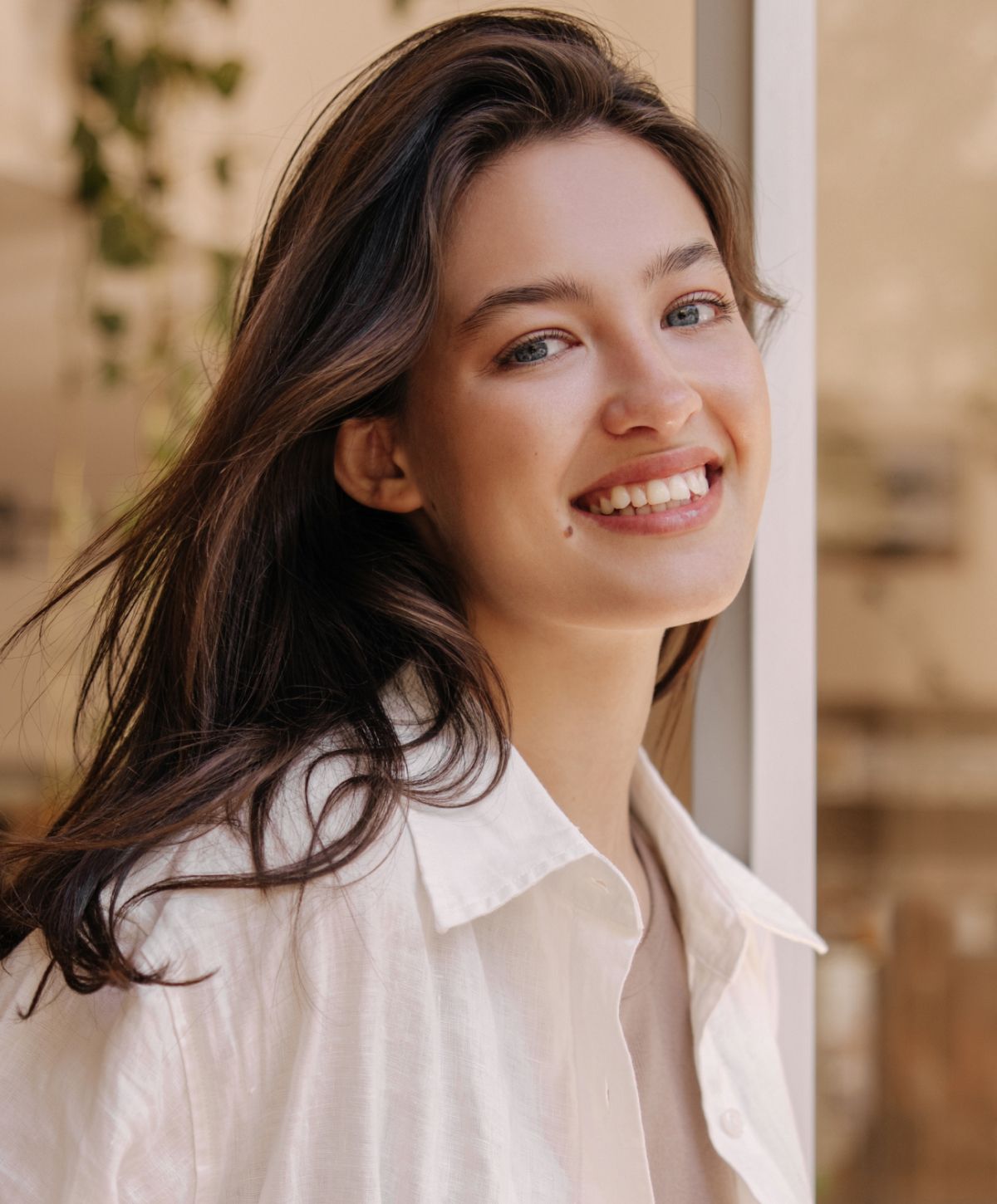Smiling woman with long hair in natural light.
