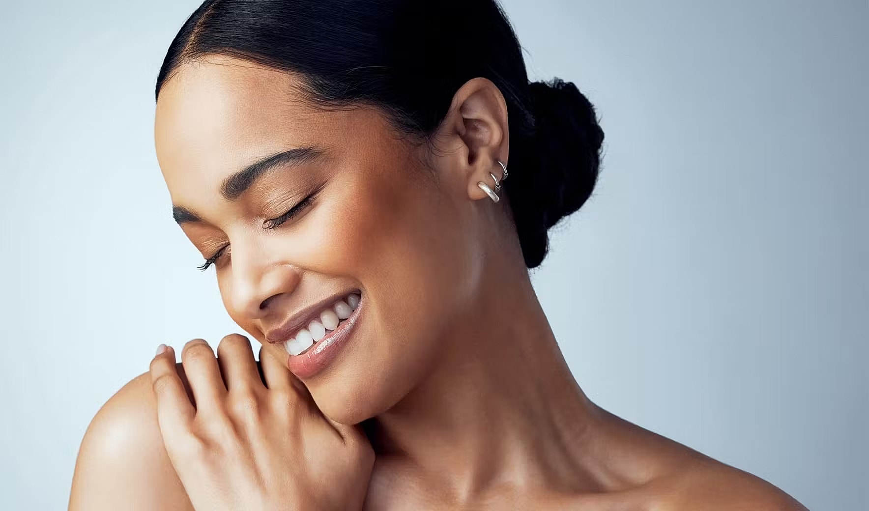 Smiling woman with a serene expression and jewelry.