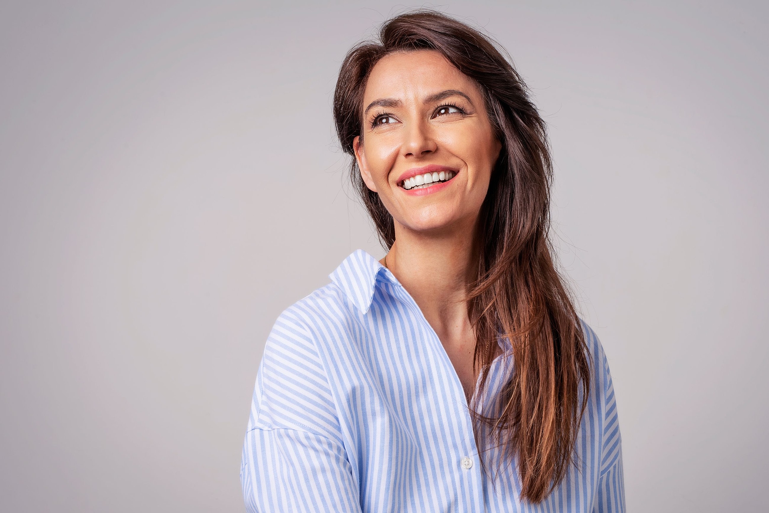 Smiling woman with natural facial contours, representing deep plane facelift results that look refreshed and not pulled.