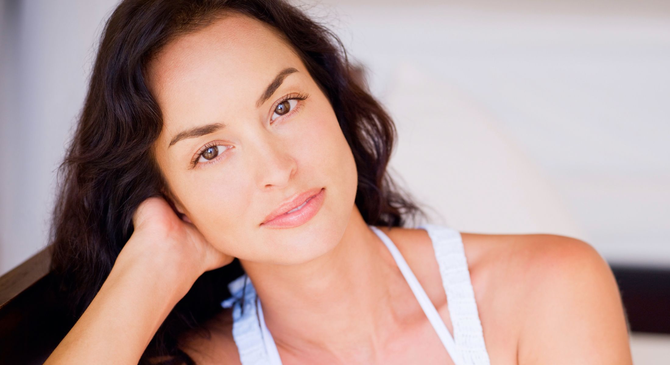Thoughtful woman with long, dark, wavy hair.