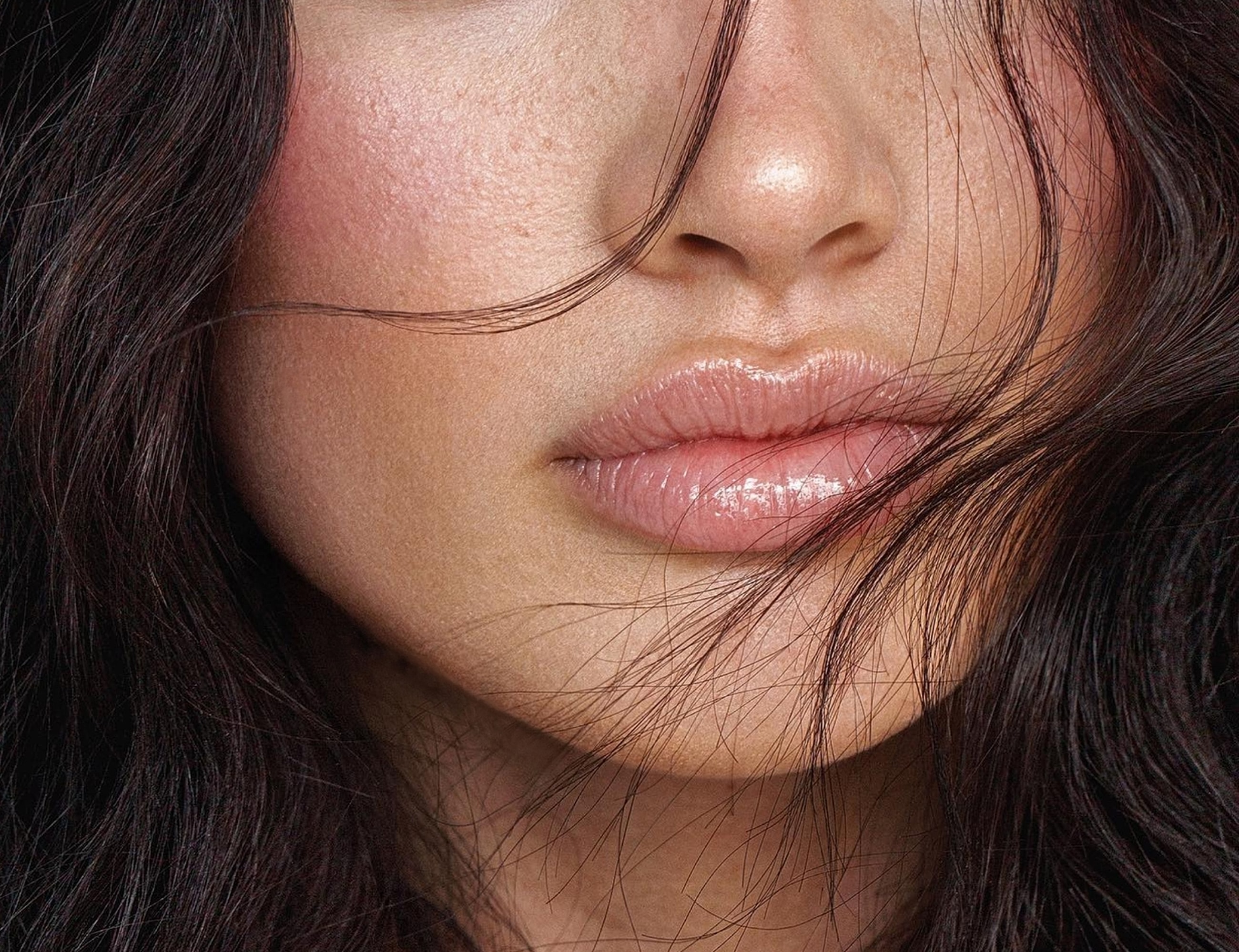 Close-up of lips with loose hair strands.