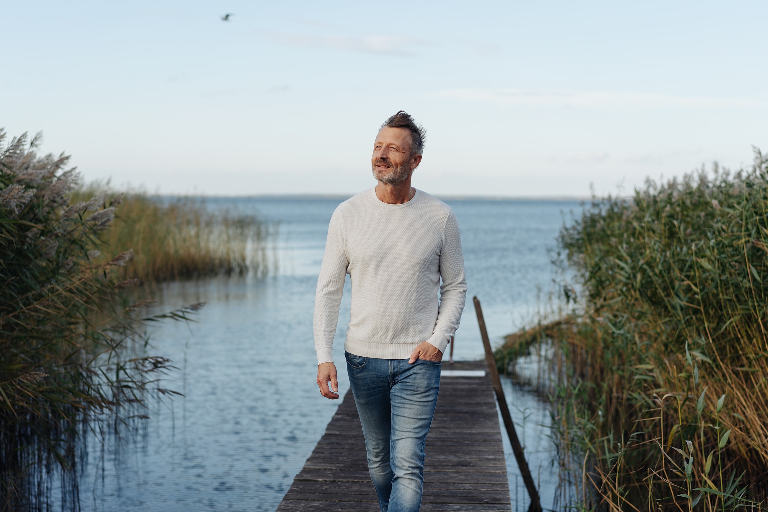 Man walking on pier by water.